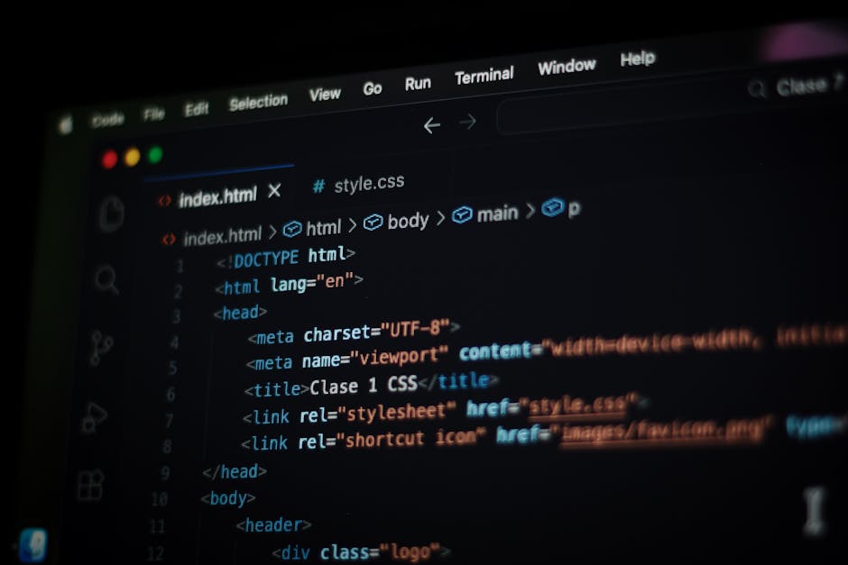 A close-up photograph of a laptop computer displaying lines of source code on a dark background, positioned on a wooden desk surface. To the right of the laptop, there is a ceramic coffee mug with a b